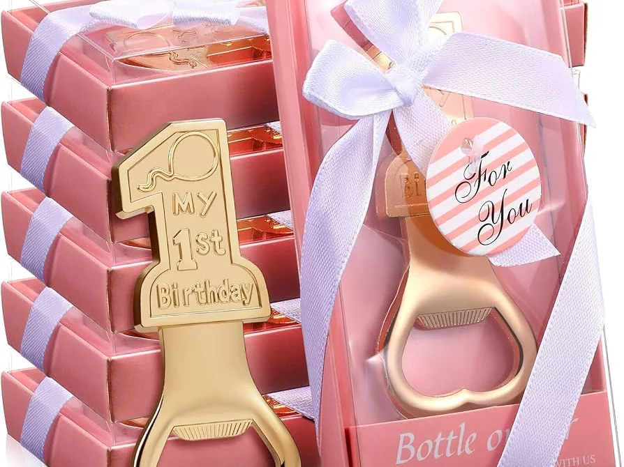 Pink gift boxes holding gold 'My 1st Birthday' keepsake bottle openers, tied with white ribbon and a 'For You' tag